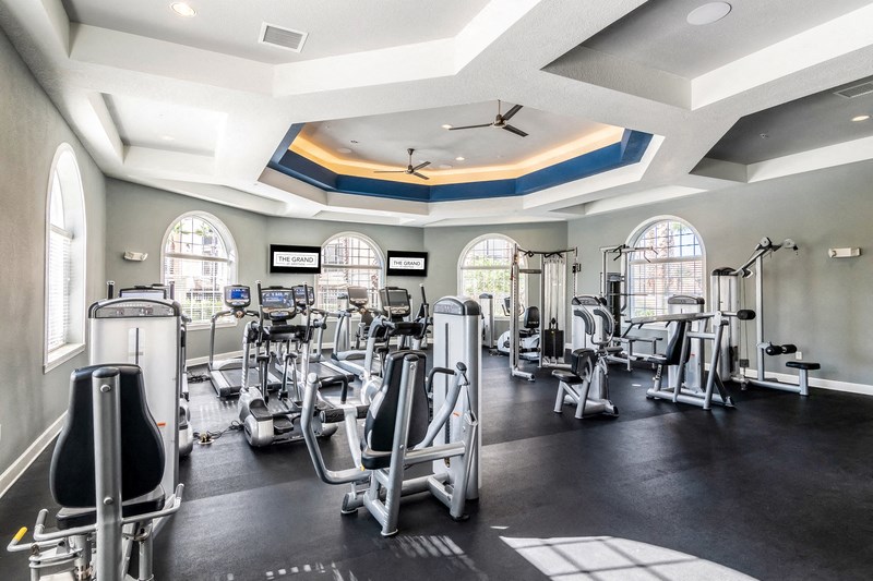 a gym with cardio equipment and windows