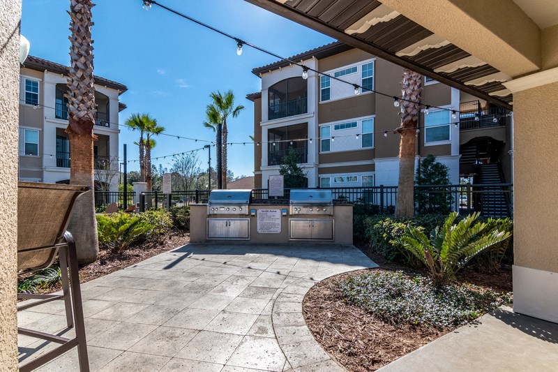 an outdoor patio with a grill and a table with chairs in an apartment building