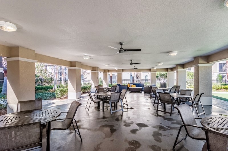 a patio with tables and chairs and a ceiling fan