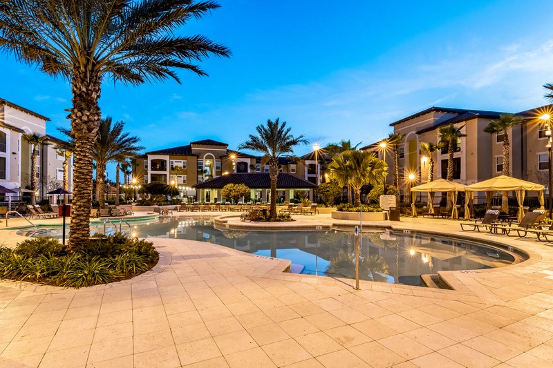 a swimming pool with palm trees and buildings in the background