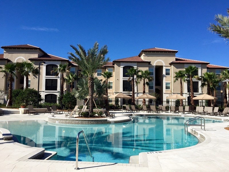 a large swimming pool with palm trees in front of a hotel