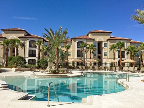 a large swimming pool with palm trees in front of a building