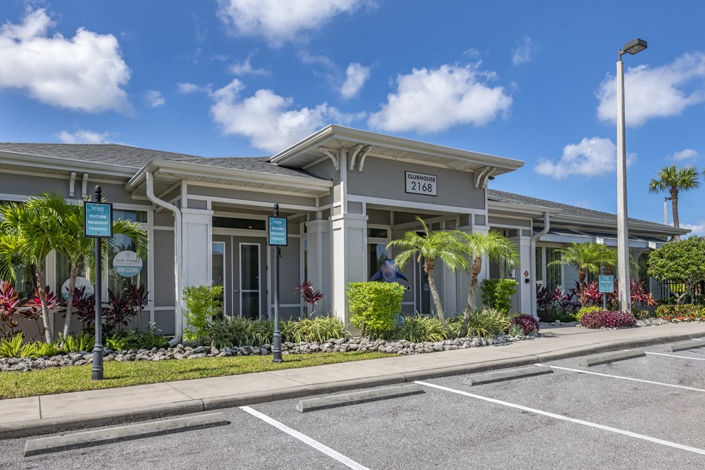 the front of a building with palm trees and a parking lot