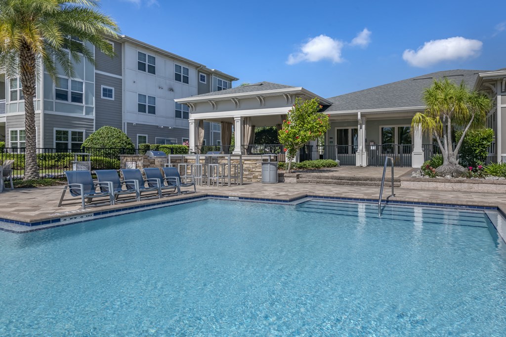 a large swimming pool with chairs in front of an apartment building