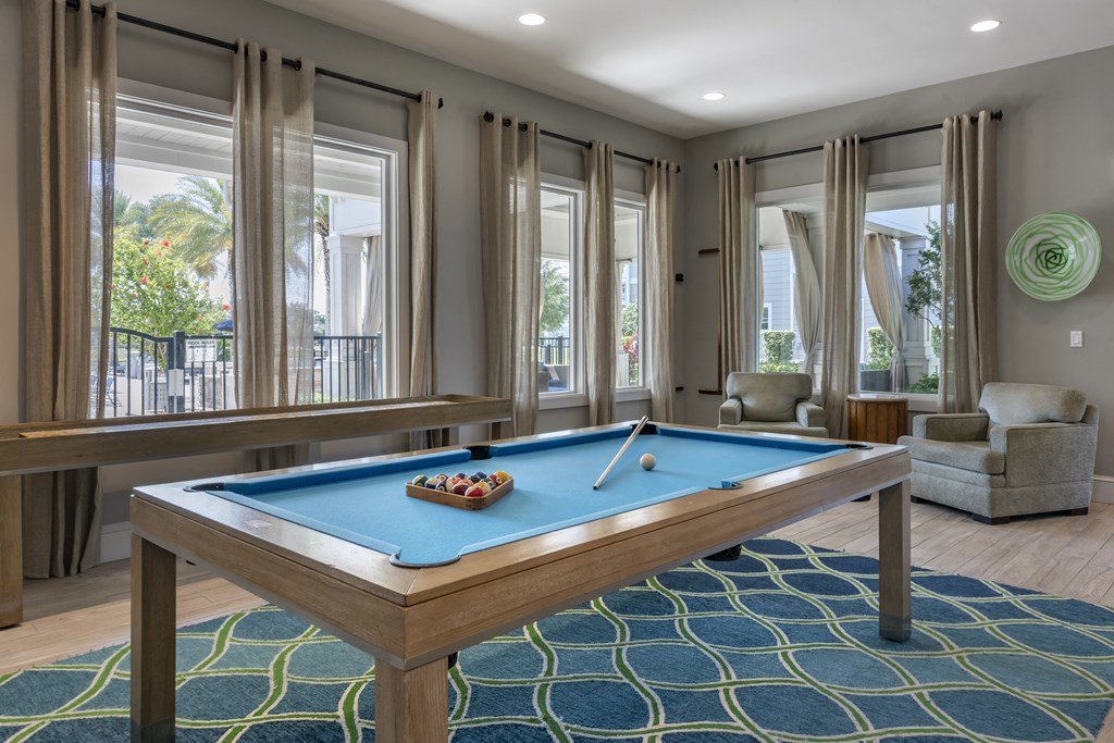 a games room with a pool table and windows