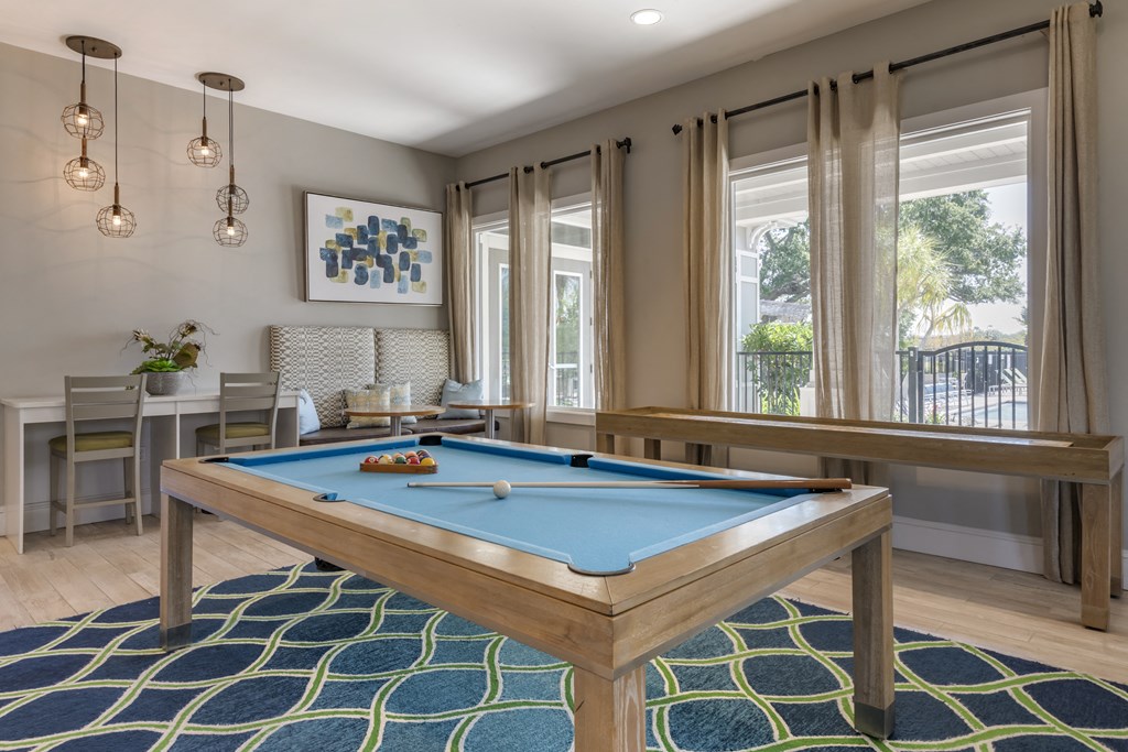 a billiards table in a game room with windows