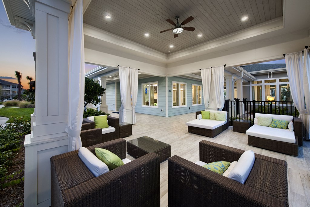 a covered patio with wicker furniture and a ceiling fan