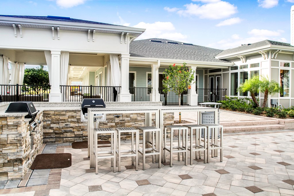 a patio with a bar and chairs in front of a house