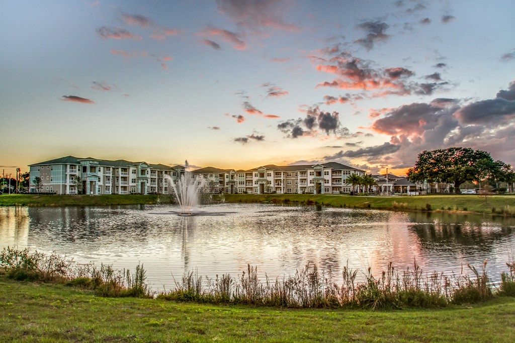 a fountain in the pond with an apartment building in the background