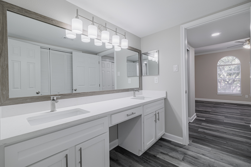 bathroom with dual vanities, white countertops and cabinetry