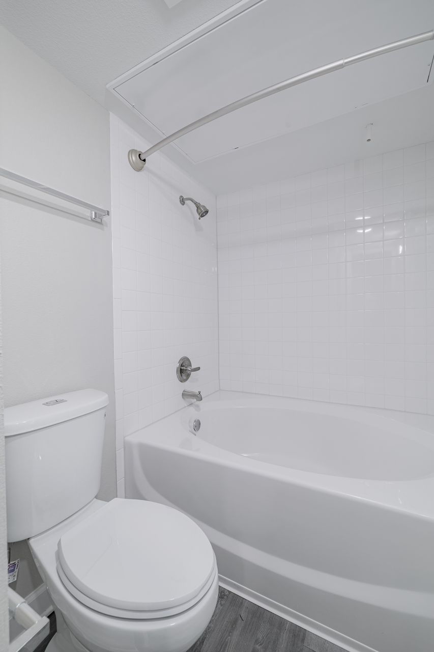 a white bathroom with a toilet and a tub
