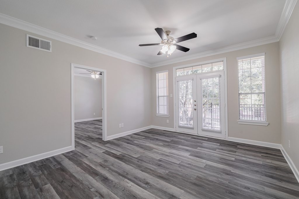an empty living room with a ceiling fan and windows