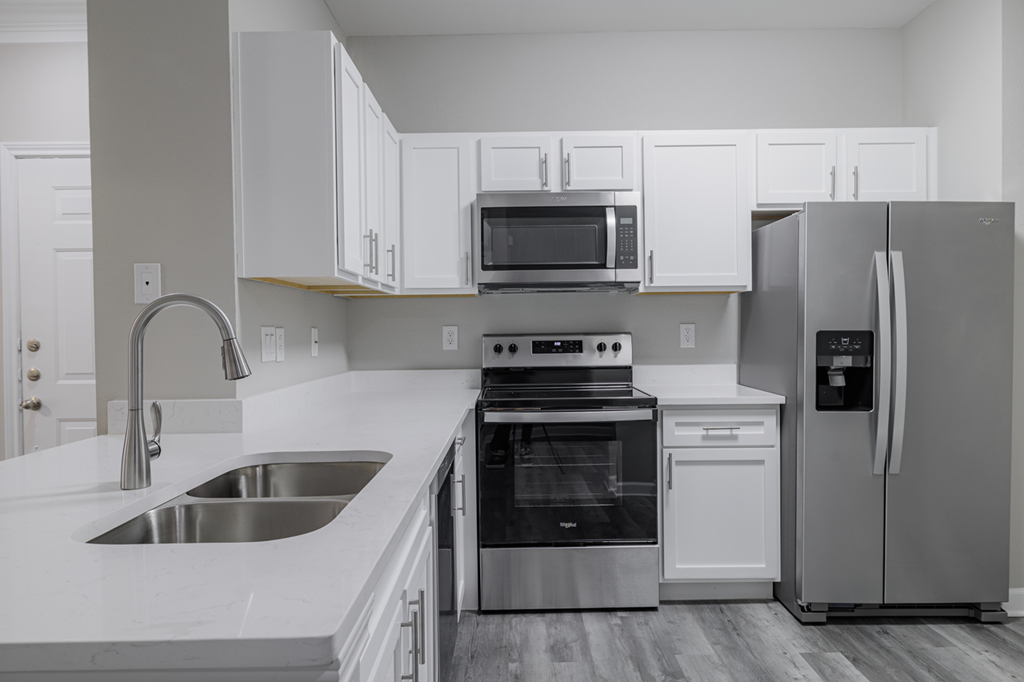 kitchen with stainless appliances, white countertops, and hardwood-style flooring