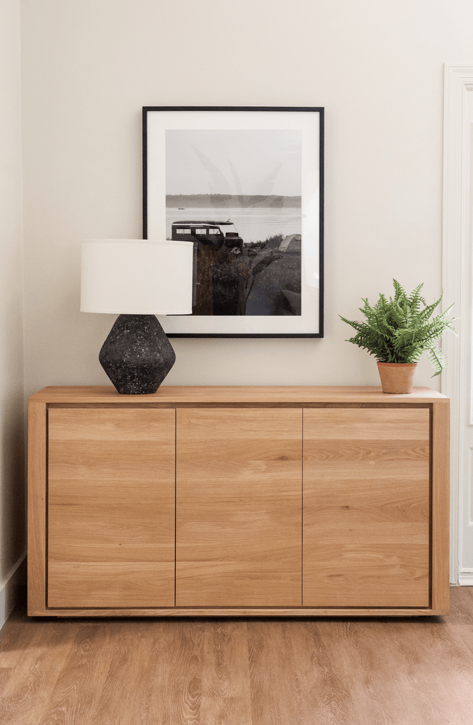 a wooden dresser with a lamp and a picture on the wall