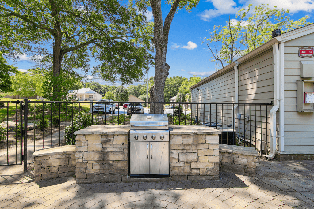 an outdoor kitchen with a stone wall and a stainless steel stove