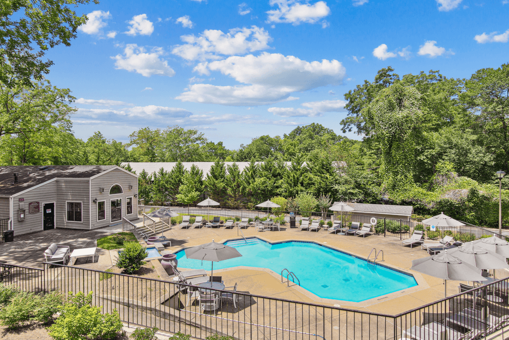 a swimming pool with umbrellas and chairs around it and a building with trees