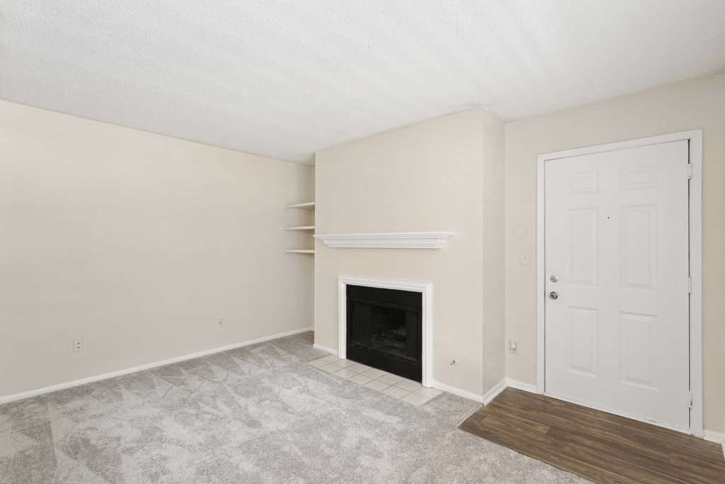 an empty living room with a fireplace and a door