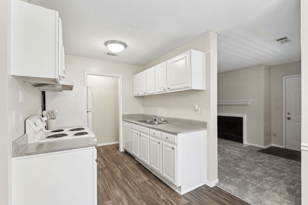 an empty kitchen with white cabinets and a stove and a refrigerator