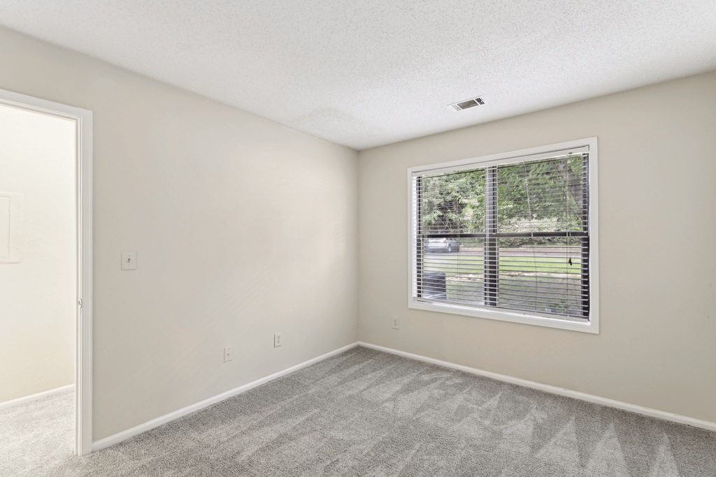 an empty bedroom with a large window and a carpeted floor
