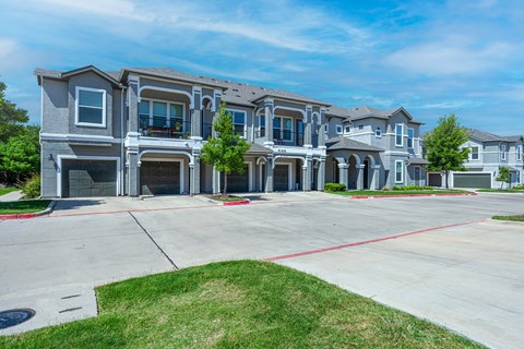 A row of apartments with grey exteriors and red outlines on the driveways.