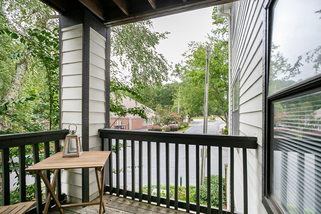 A table with a lantern on a porch overlooking a street.