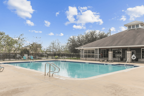A swimming pool with a diving board and a small building in the background.