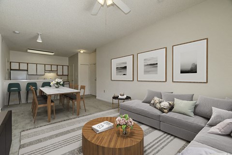 A living room with a grey couch, a wooden coffee table, and a dining table with chairs.