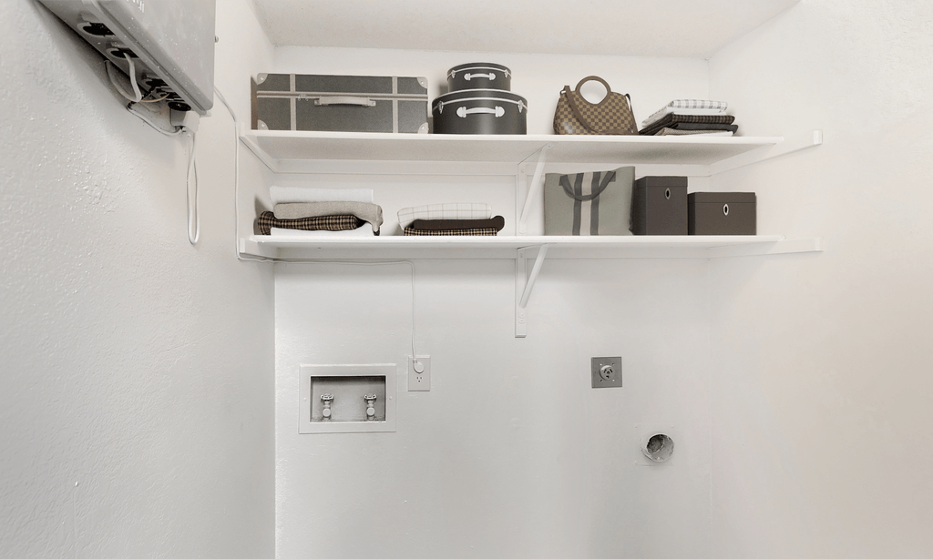 Laundry area with washer and dryer connections, shelves with bags and boxes