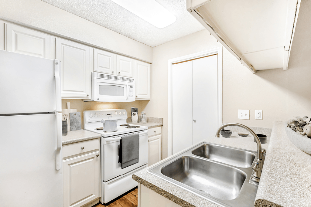 Virtually staged kitchen with granite inspired countertops, white appliances, white cabinetry, double basin sink, pot on stove and cutting boards