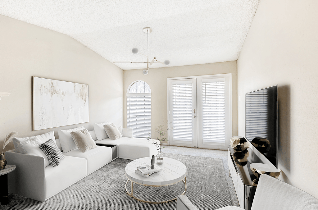 Virtually staged livingroom with carpet, accent rug, white couch with white coffee table, hanging light fixture, vaulted ceiling, tv stand with large tv and windows and doors with blinds