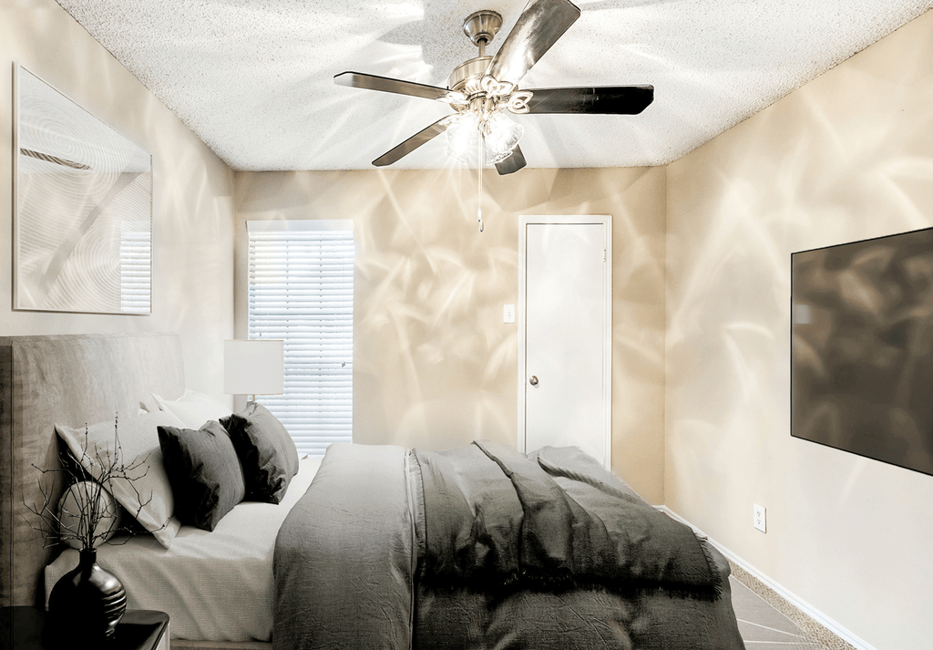 Virtually staged bedroom with carpet, accent rug, bed, side tables, wall mounted television and window with blinds