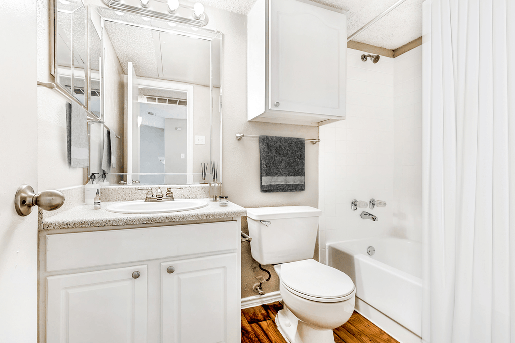 Virtually staged bathroom with granite inspired countertops, medicine cabinet, custom vanity mirrors, and white cabinetry with sheer shower curtain