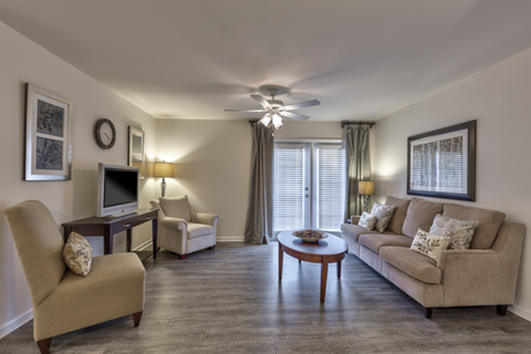 A living room with a beige sofa, two chairs, a coffee table, and a television.
