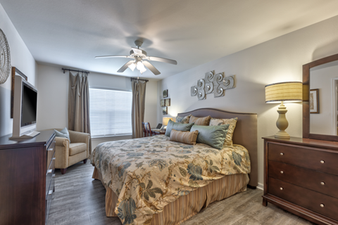 A bedroom with a large bed and a ceiling fan.