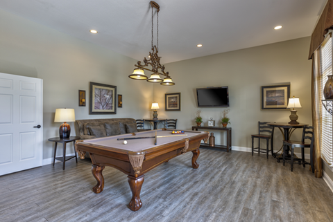 A pool table is in the middle of a room with a tv and a couch.