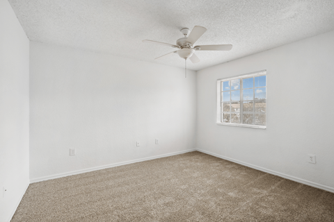 an empty room with carpet and a ceiling fan