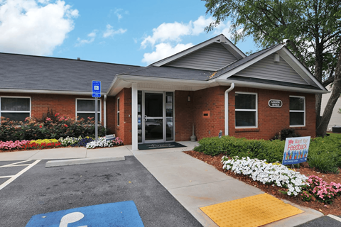 Brick building with large windows and walkway leading to entrance of the leasing office.