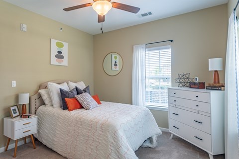 A bedroom with a bed, dresser, and window.
