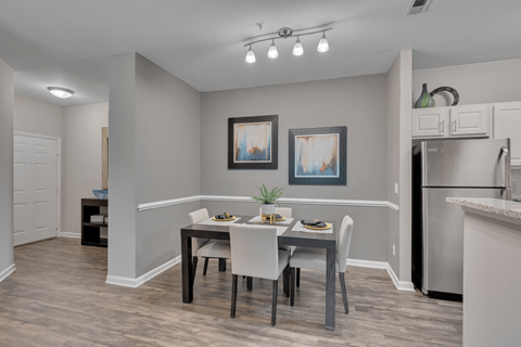 A dining room with a table set for two and a potted plant on the table.