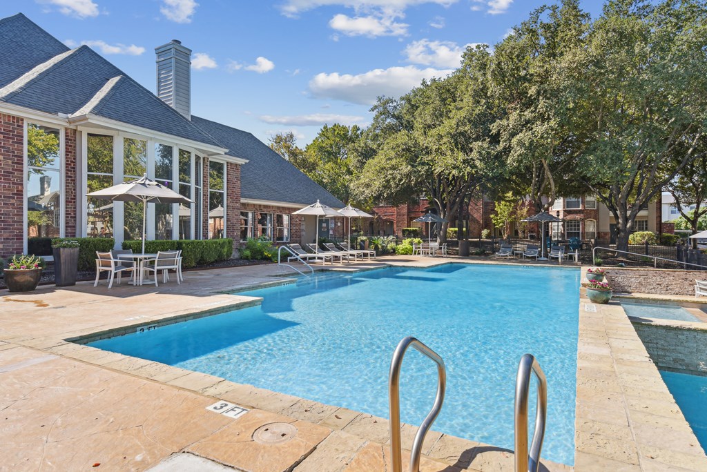 A large swimming pool with a diving board in front of a house.