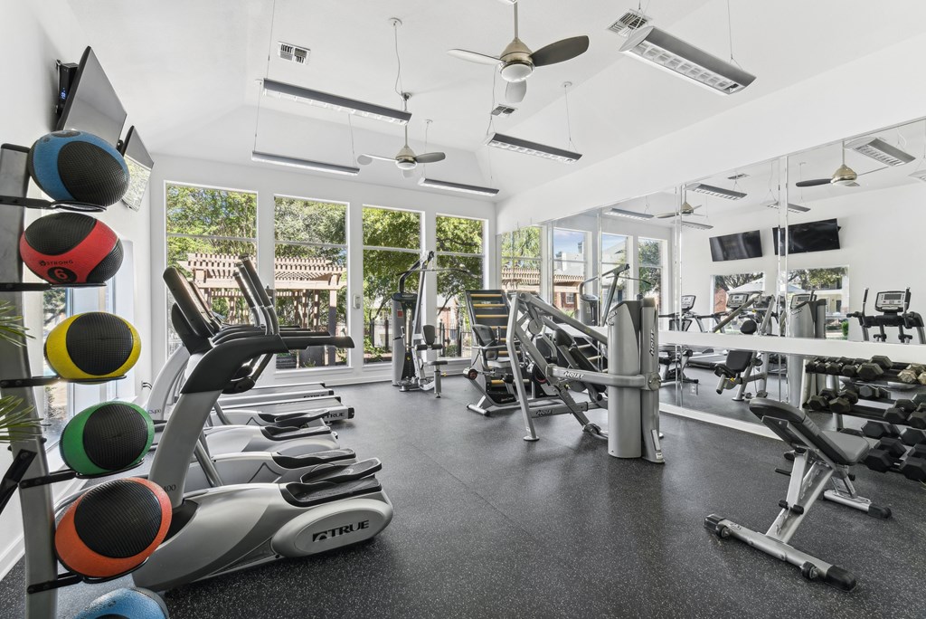 A gym with a variety of equipment including treadmills, weights, and exercise machines.