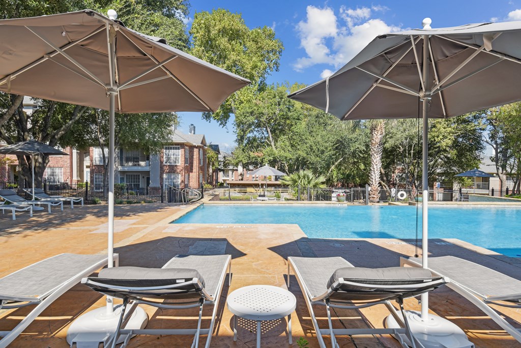 A pool area with sun loungers and umbrellas.
