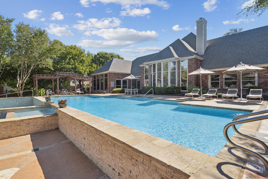 A large swimming pool with a stone wall and a metal railing.