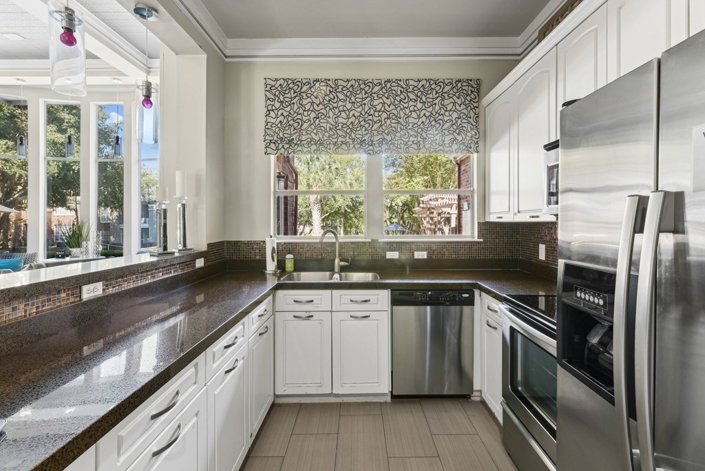 A modern kitchen with white cabinets and stainless steel appliances.