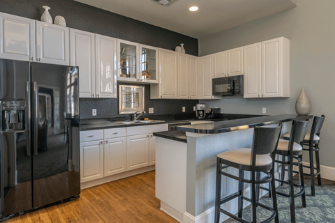 a kitchen with white cabinets and black countertops
