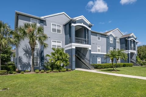 2-story blue apartment building with grass and trees