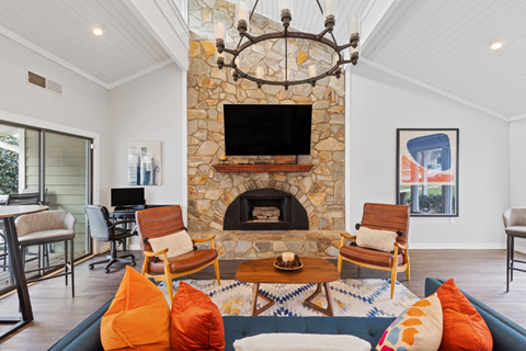 A living room with a stone fireplace and a flat screen TV mounted above it.