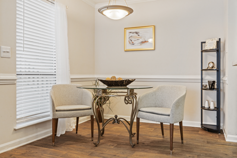 A dining room with a table and two chairs.