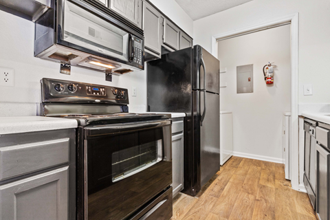 A black fridge and oven in a kitchen with wooden floors.