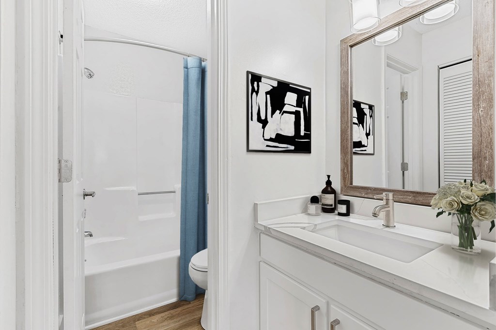 A white bathroom with a white sink and a white toilet. at Woodlyn on the Green Apartment Homes, Cary, 27513
